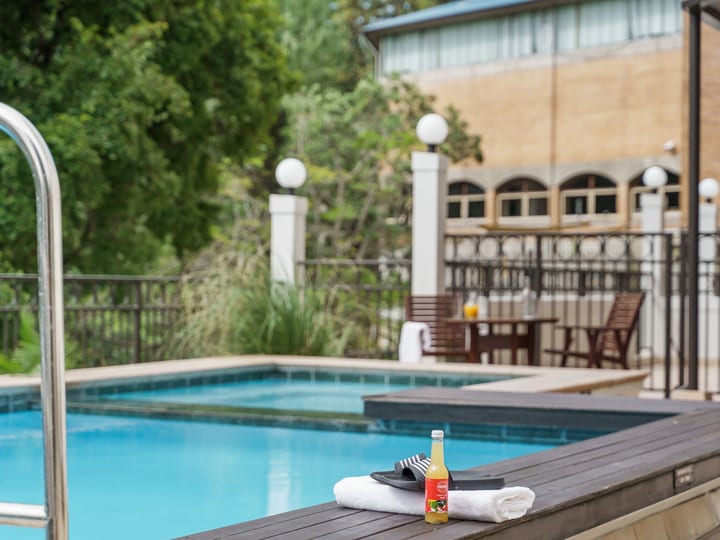 Outdoor tiled pool with timber deck, iron balustrade and multi-storey building behind