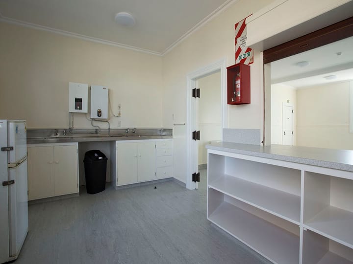 Plain cream kitchen with stainless sinks, cabinetry, and a serving hatch to another room