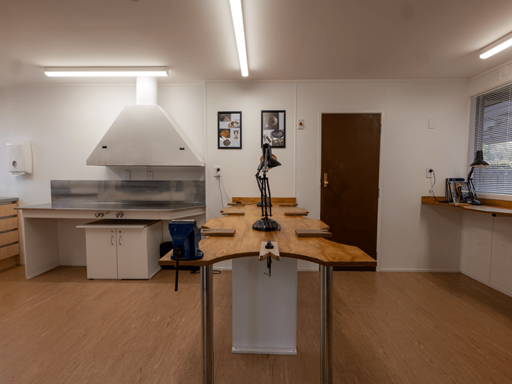 Workshop room with live-edge timber workbench, task lamps and extraction hood