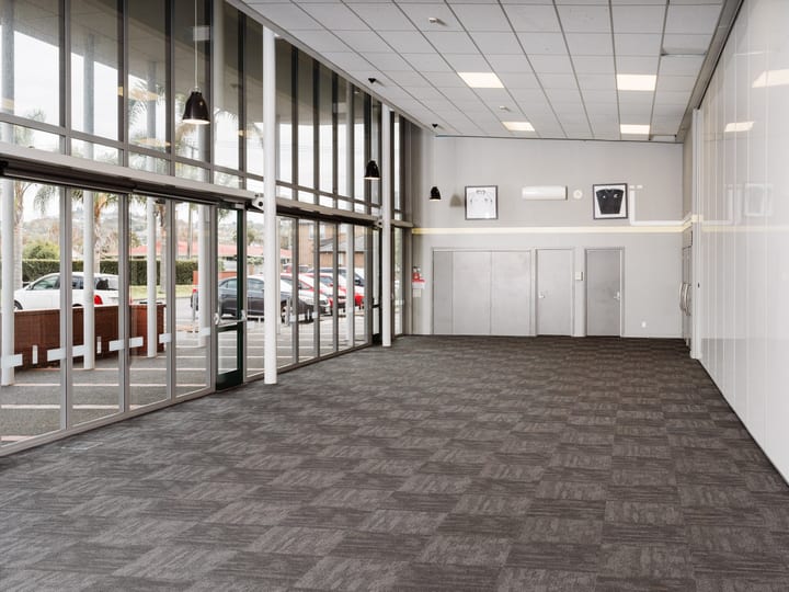 Foyer entrance with full-height glazing, carpet tiles, pendant lights, and open plan layout