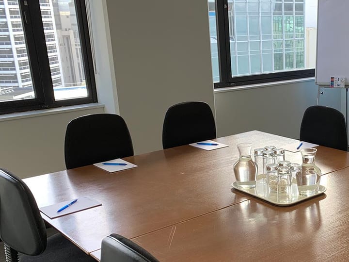 Small boardroom with central table, dark chairs, and whiteboard