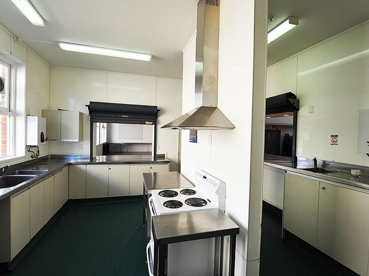 L-shaped kitchen with stainless benchtops, serving hatch and white cabinetry