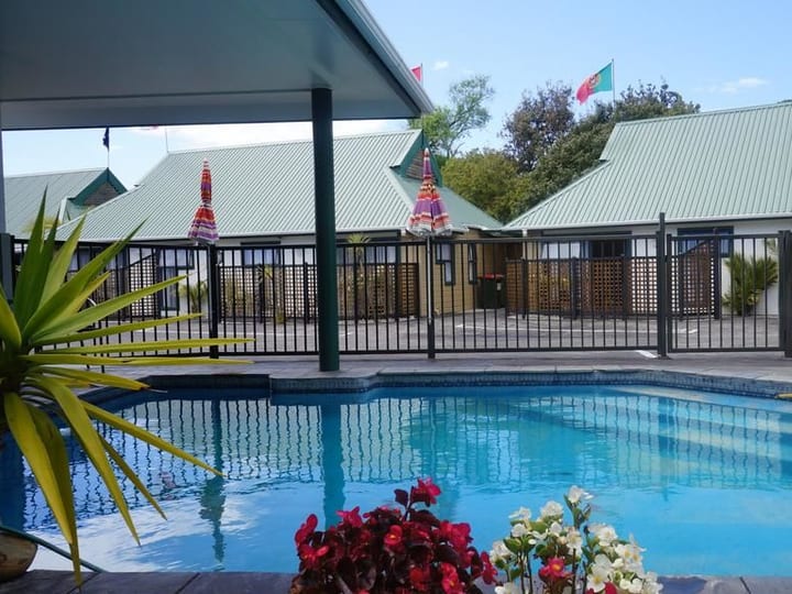 Outdoor pool area with umbrellas and low-set buildings behind
