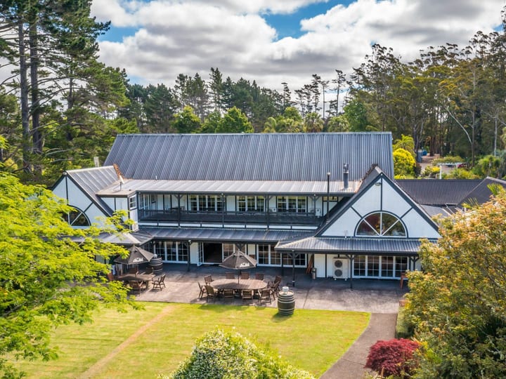 Lodge building with steeply pitched roof set among trees with outdoor dining area
