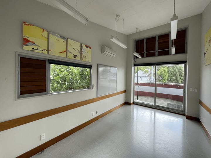 Small plain room with carpet tiles, kitchenette and sliding glass door