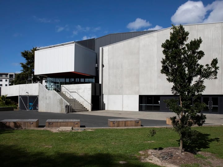 Large concrete and metal events building with external steps and timber seating, open grounds