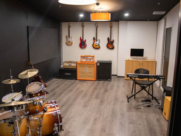 Small rehearsal room with acoustic panels, drum kit, guitars and keyboard