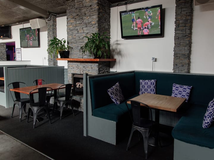 Bar interior with high tables, bar stools and multiple TV screens showing sport