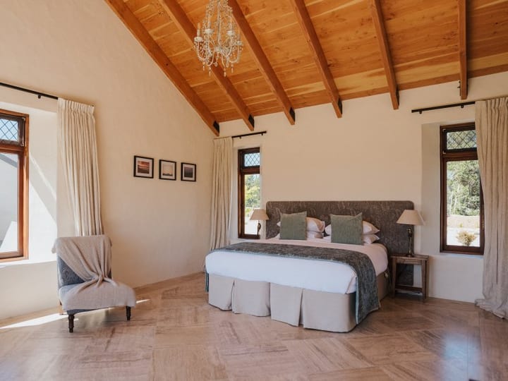 King bedroom with timber beam ceiling, upholstered bedhead and leaded windows