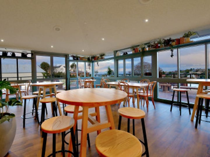 Dining and bar area with large windows, round tables and stools