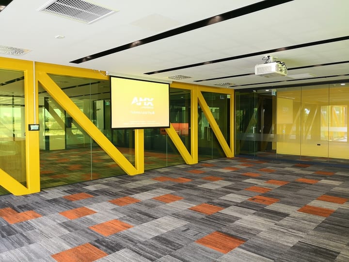 Large open event space with yellow structural frames and colourful carpet