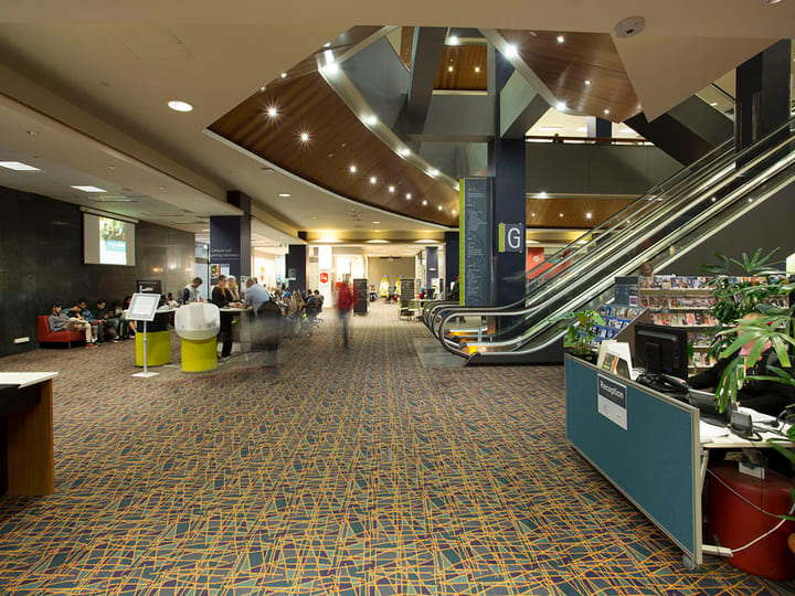 Library ground floor with escalator, reception desk and curved timber ceiling