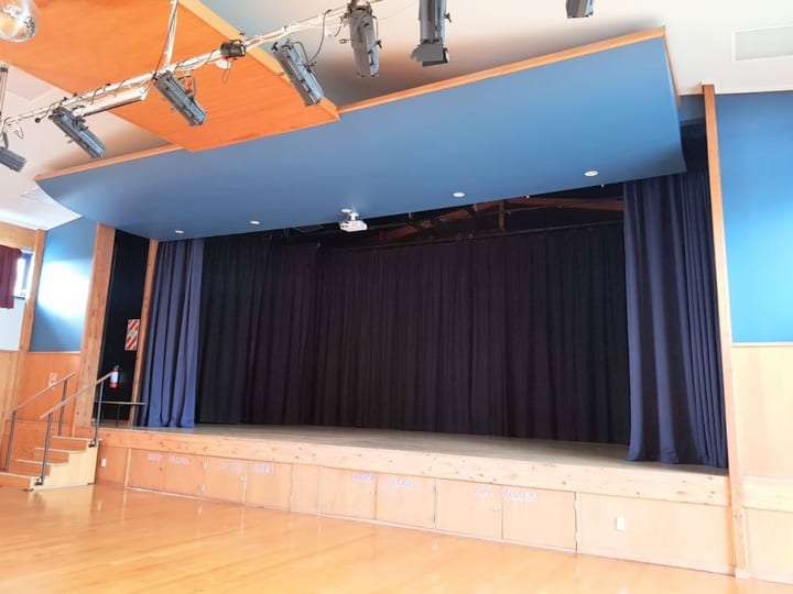 Raised platform with blue curtain and stage lighting rig above