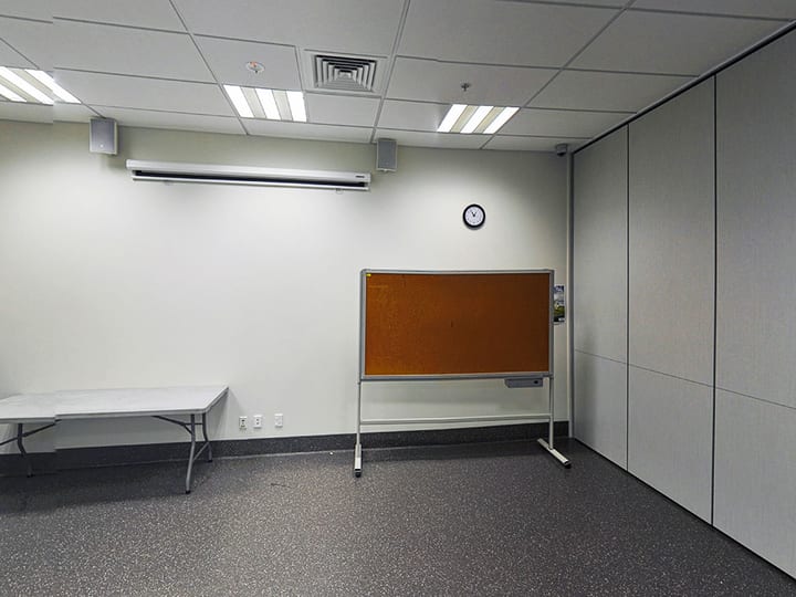 Empty meeting room with cork noticeboard, air conditioning unit and folding partition