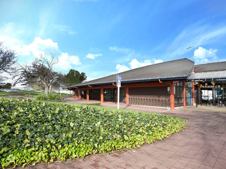 Single-storey library building with timber roof and hedge-lined frontage