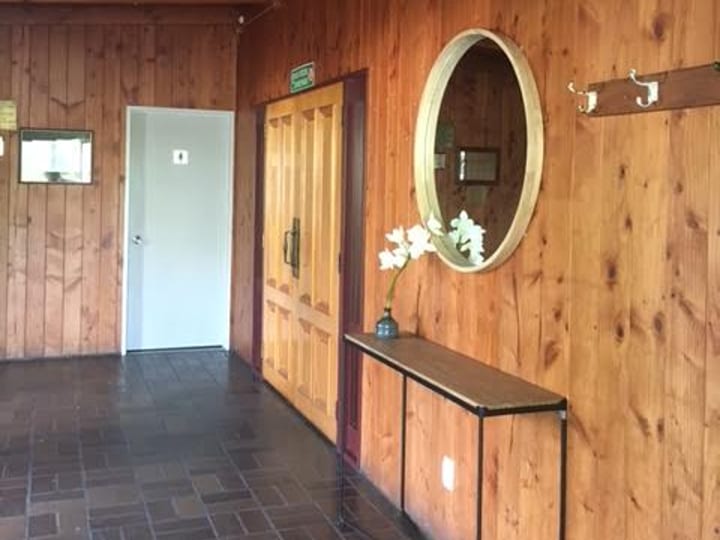 Timber-panelled hallway entrance with round mirror, flower arrangement, and coat hooks
