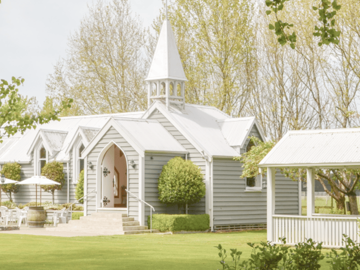White chapel with steeple on manicured lawn with mature trees