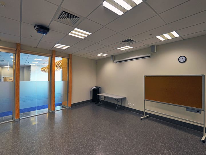 Plain meeting room with cork noticeboard, projector and glass partition wall