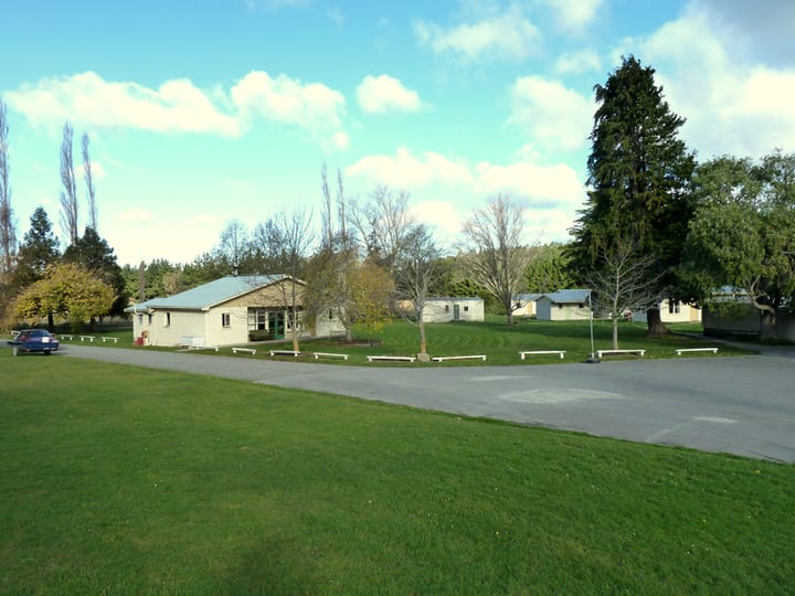 Camp grounds with low buildings, grass lawn and mature trees