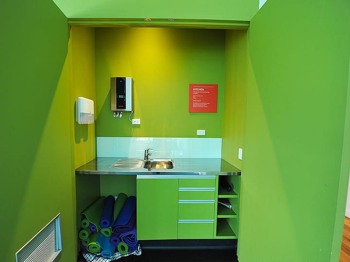 Small kitchenette with green walls, sink, and storage