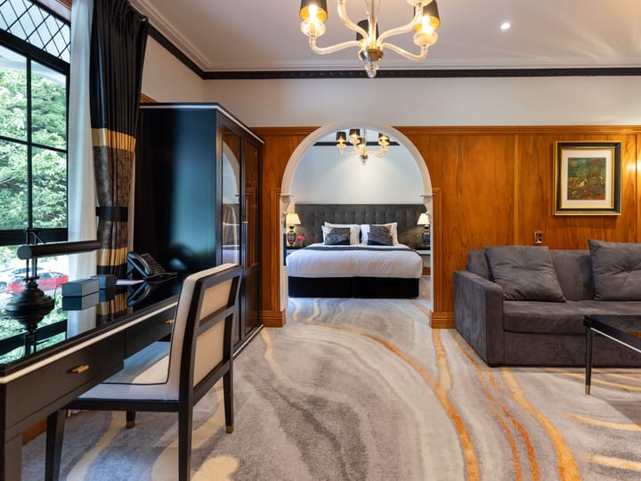 Hotel suite with sitting room, chandelier, and arched doorway to bedroom