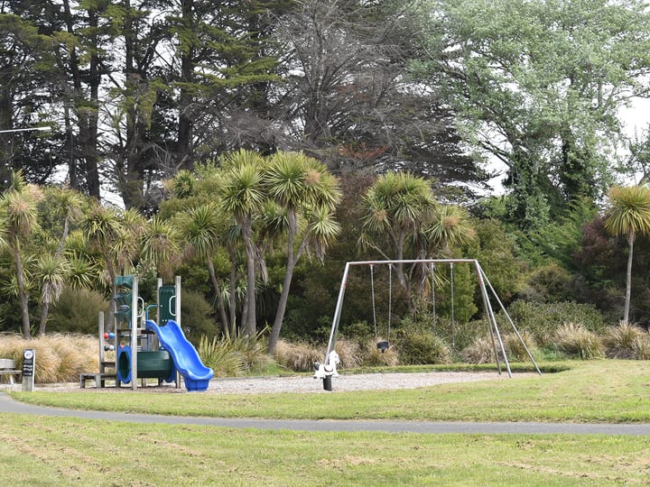 Park playground with slide, swings and trees