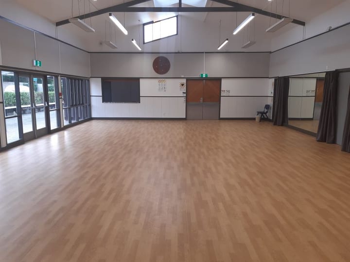 Empty hall with timber floor, vaulted ceiling and stained glass window accent