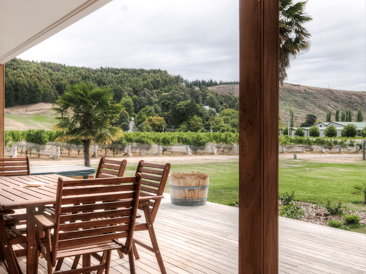 Covered timber deck with outdoor furniture overlooking vineyard rows and hills