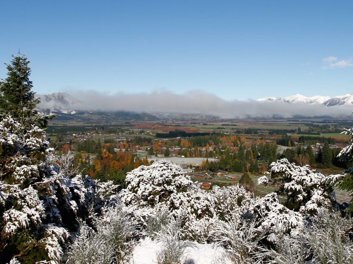 Snowy valley and mountain range viewed through frost-covered trees