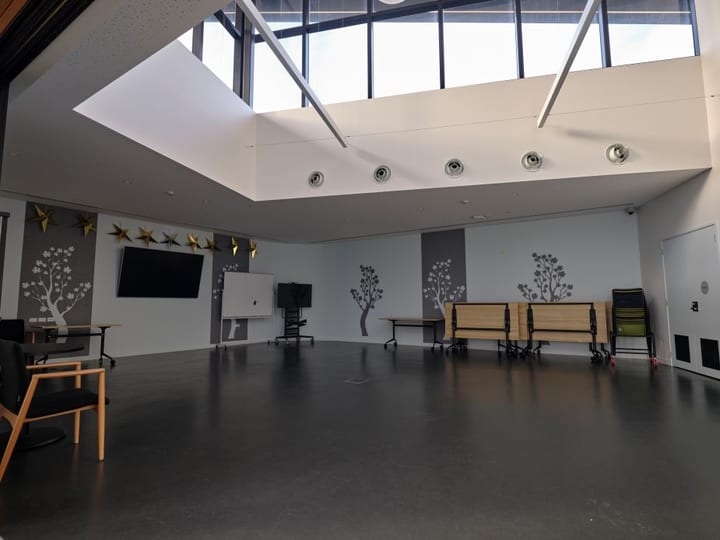 Flexible hall with large skylight roof, painted tree murals on grey walls, and folded tables to one side