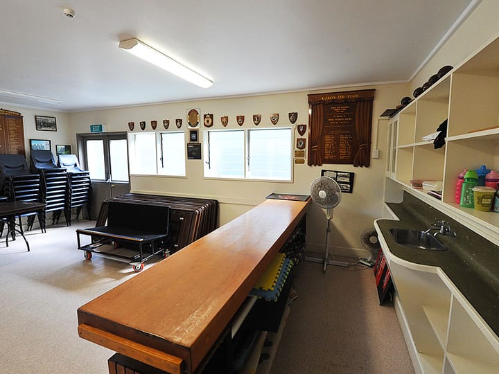 Hall room with stacked chairs, tables, bar counter and memorial plaques on wall