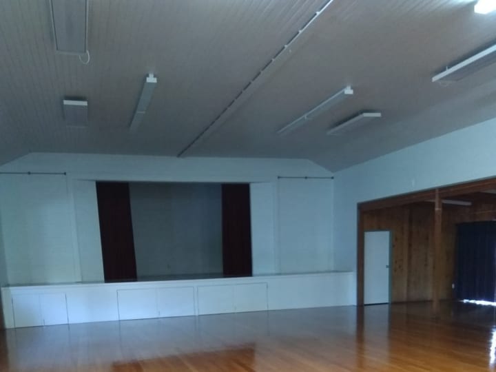 Main hall with polished timber floor and stage drapes at one end