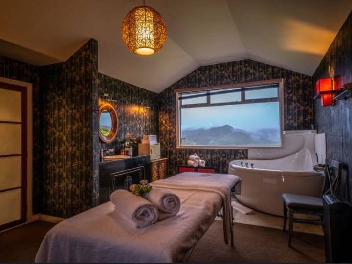Lodge bedroom with floral wallpaper, double bed, and hillside view