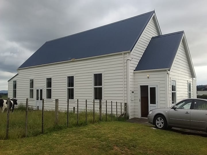 White weatherboard hall with blue iron roof, set in rural paddock