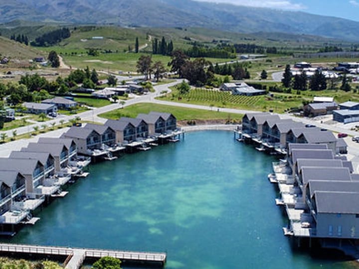 Aerial view of lakeside resort with rows of cabins and marina, mountains behind