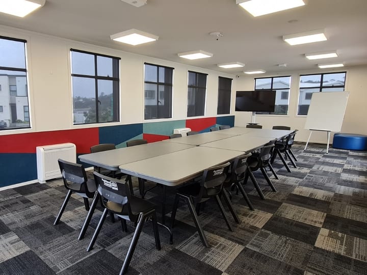 Meeting room with long table, chairs, screen, and whiteboard