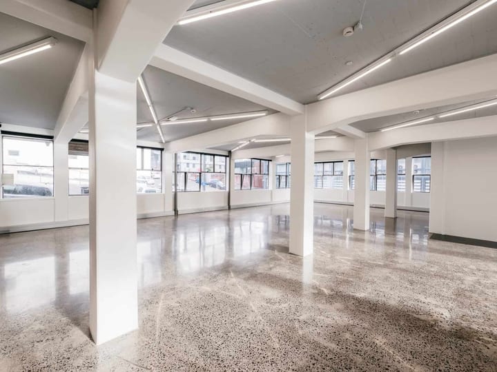 White industrial space with polished concrete floor, structural columns, and row windows