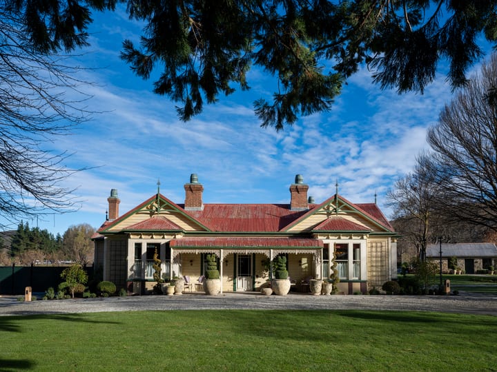 Victorian homestead building at Ayrburn with ornate verandah, topiary urns, and open lawn in foreground
