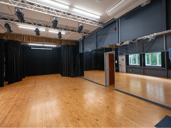 Dance studio with mirror wall, stage lighting and black curtains