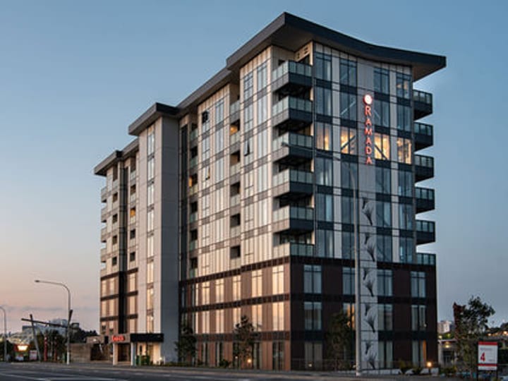 Multi-storey hotel building with glazed facade lit at dusk on city street