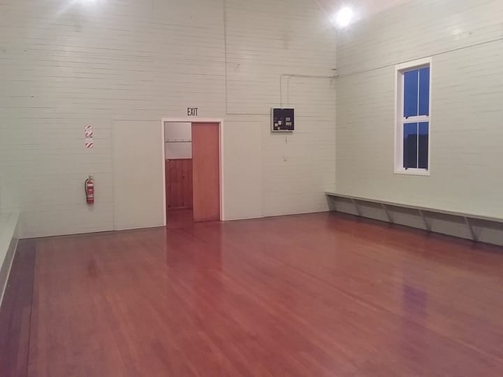 Empty white hall interior with polished timber floor and wall bench seating