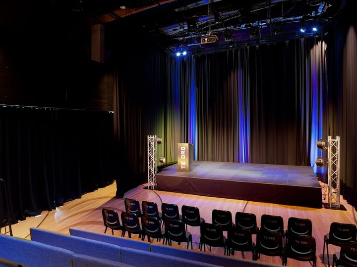 Theatre with raised stage, draped curtains and tiered fixed seating