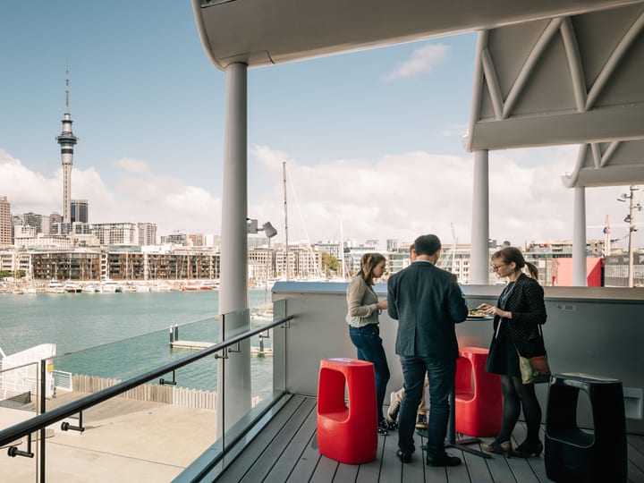 Open balcony deck overlooking harbour with city skyline and sky tower in background