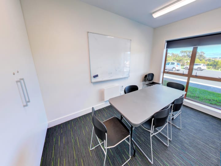 Small meeting room with table, chairs, and whiteboard