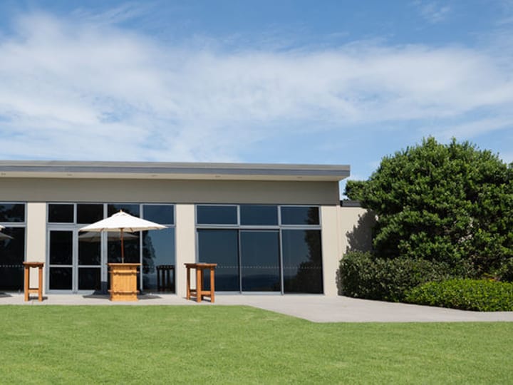 Single-storey venue building with full-height glazing and lawn in front