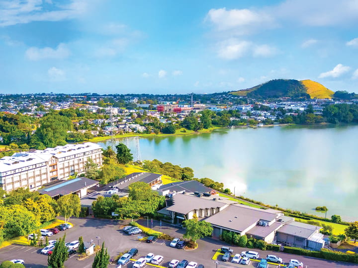 Aerial view of hotel buildings beside a lake with a volcanic hill beyond