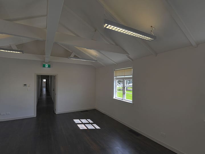 Empty hall with exposed timber roof trusses and dark timber floor
