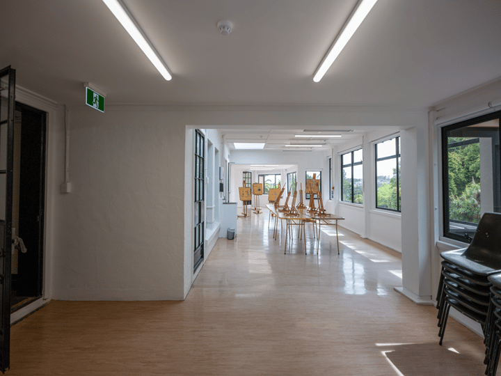 Long corridor with art studio visible at the end, easels and stacked chairs