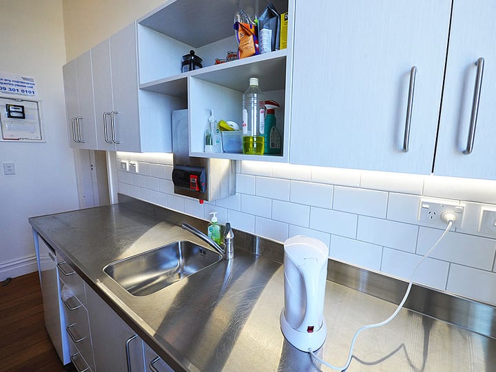 Another angle of compact kitchen with grey cabinets and stainless bench
