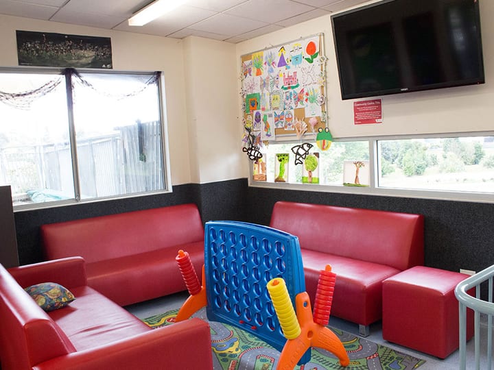 Children's lounge with red seating, noticeboard and games